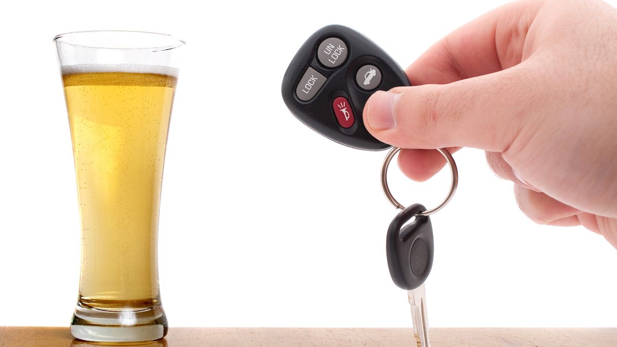 Alcoholic Beverage And Hand Holding Car Key Suggest A DUI With Alcohol Assessment